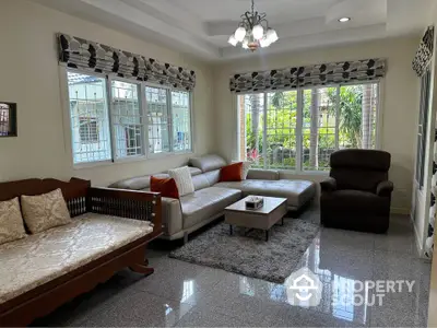 Spacious living room with elegant furniture and large windows offering garden views.