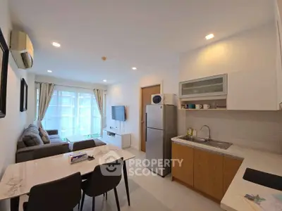Modern open-layout living room and kitchen with sleek furniture and natural light.