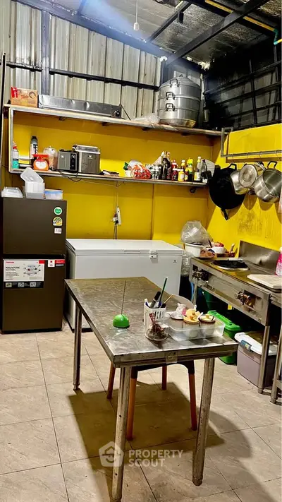 Spacious industrial-style kitchen with stainless steel appliances and vibrant yellow walls.