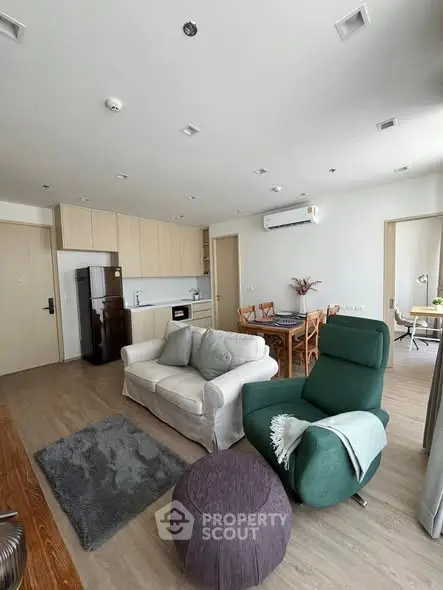 Modern living room with open kitchen, stylish furniture, and natural light.