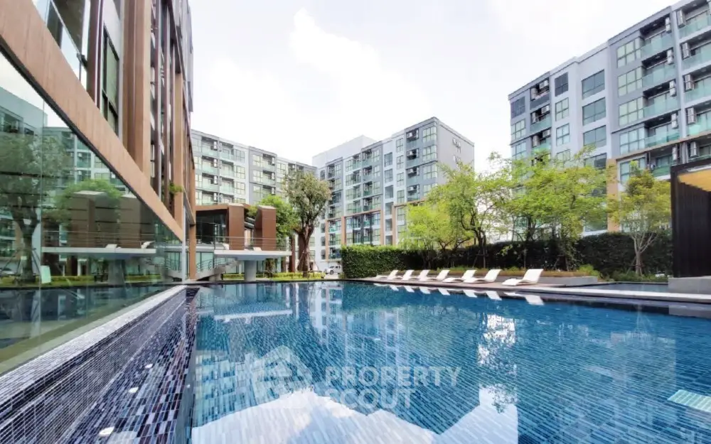 Luxurious modern apartment complex with a stunning outdoor pool and lush greenery.