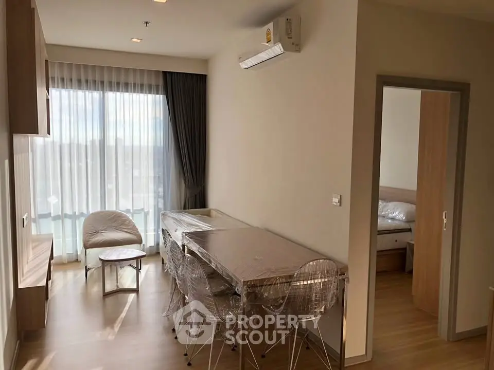 Modern apartment interior with natural light, featuring a cozy living area and a glimpse of the bedroom.
