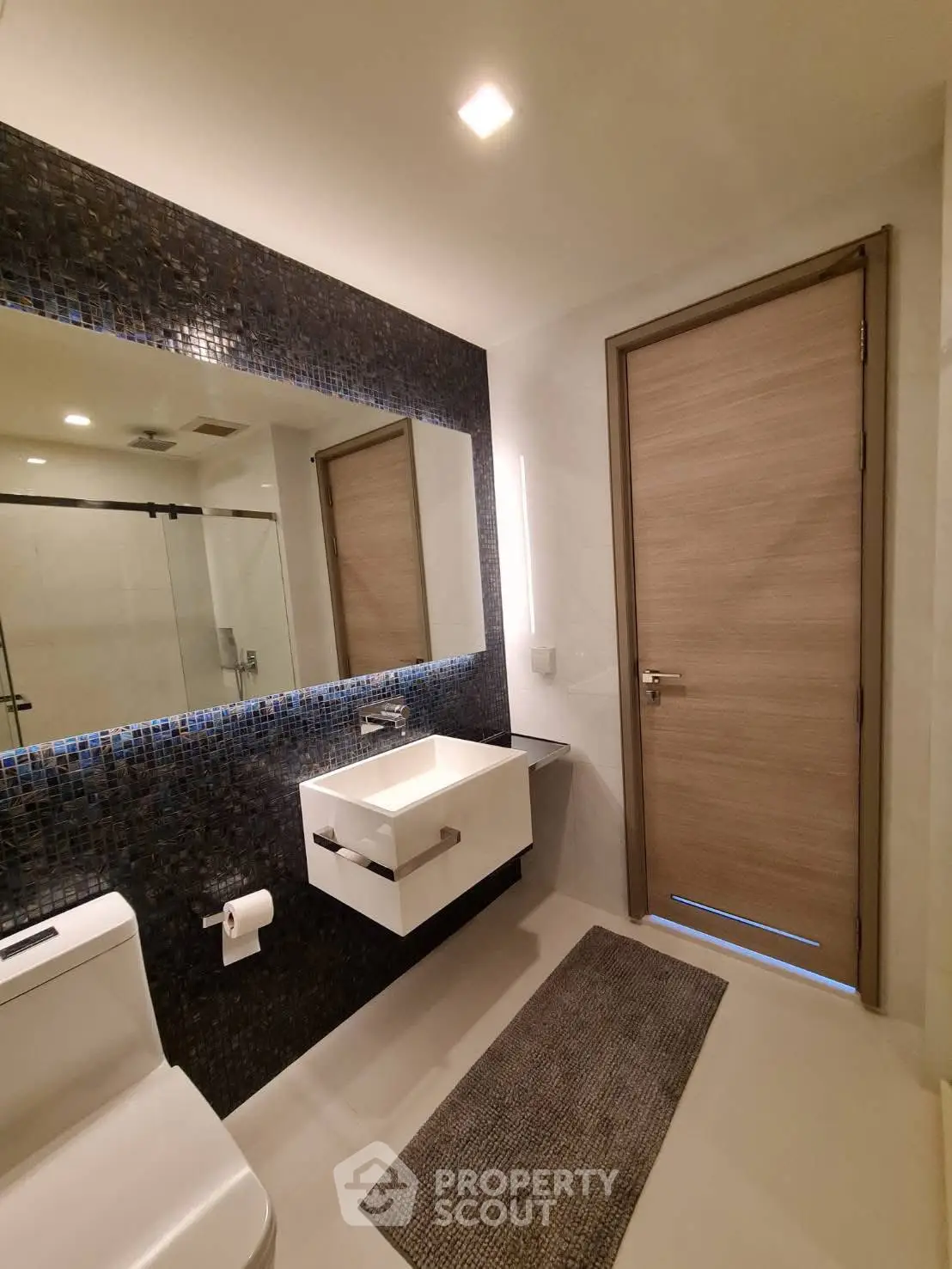 Modern bathroom with sleek design, featuring a large mirror and elegant fixtures.