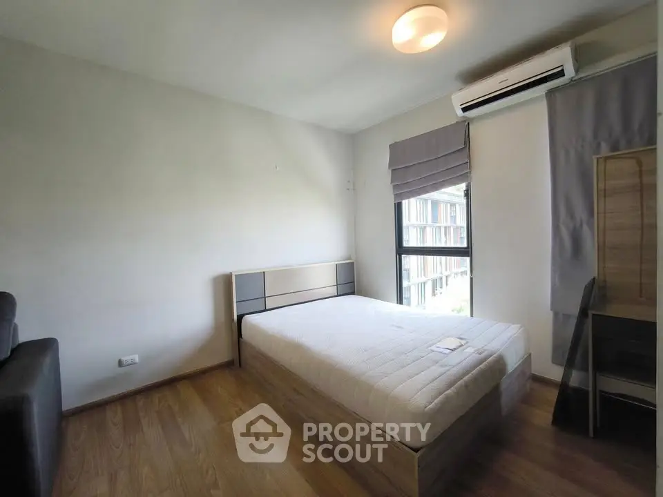 Modern bedroom with wooden flooring and large window in a stylish apartment