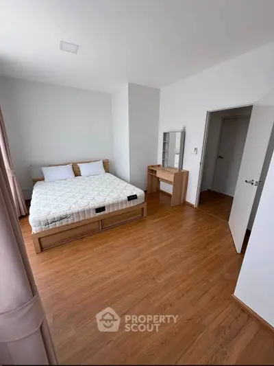 Spacious bedroom with wooden flooring and modern furniture in a stylish apartment.