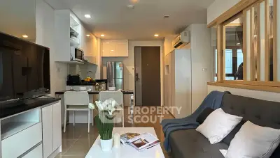 Modern open-layout living room with sleek kitchen, cozy sofa, and stylish decor in a contemporary apartment.