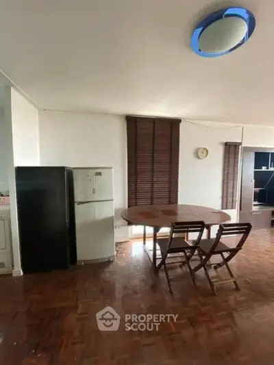 Spacious living area with wooden flooring and modern furniture, featuring a dining table and chairs.
