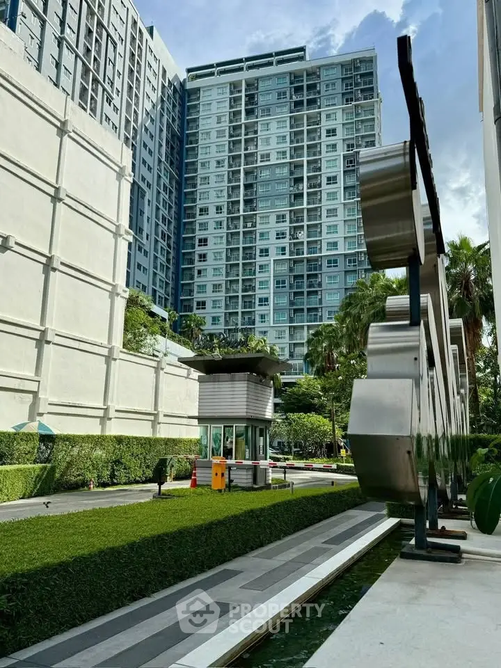 Modern high-rise building with lush landscaping and sleek architectural design.
