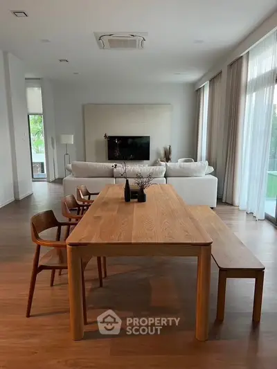 Modern open-plan living room with wooden dining table and cozy seating area.