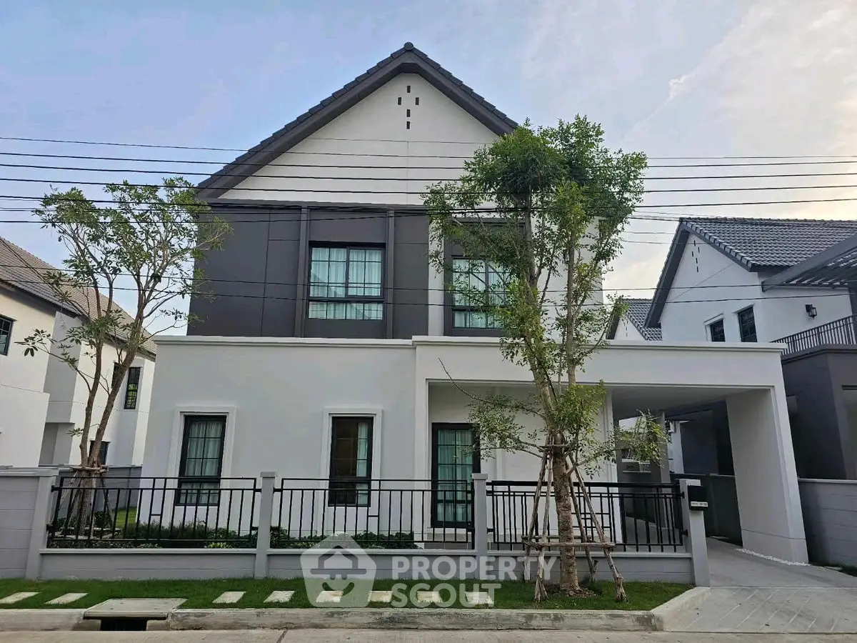 Modern two-story house with sleek design and landscaped front yard in a suburban neighborhood.