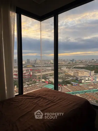Stunning corner unit bedroom with panoramic city view through large windows at sunset.