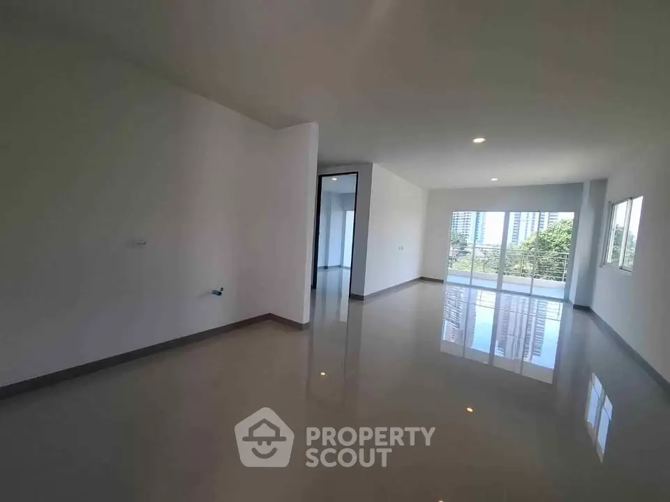 Spacious modern apartment with glossy floors and large windows offering city views.