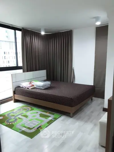Spacious bedroom with large window and modern decor in urban apartment