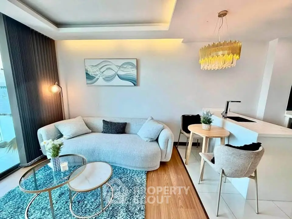 Modern living room with elegant decor and open kitchen layout, featuring stylish furniture and ambient lighting.