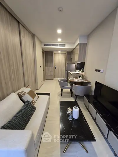 Modern living room with sleek furniture and open kitchen layout in a stylish apartment.
