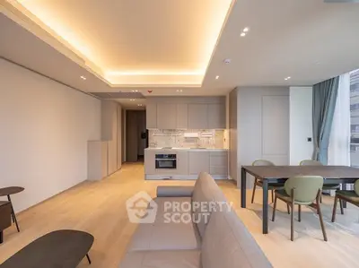 Modern open-plan living room with sleek kitchen and dining area, featuring elegant lighting and contemporary furniture.