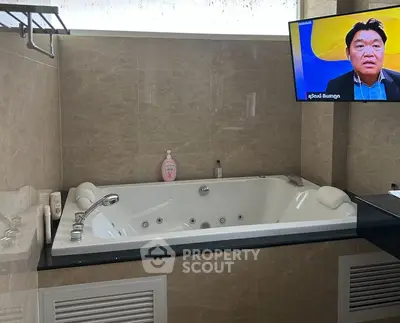 Luxurious bathroom with jacuzzi tub and mounted TV for ultimate relaxation.