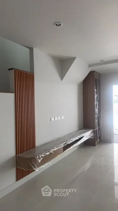 Modern minimalist living room with sleek built-in wooden furniture and neutral tones.