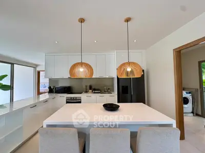 Modern kitchen with island, pendant lights, and sleek appliances in a bright open layout.