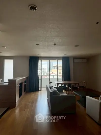 Spacious living room with modern furniture and city view through large windows.