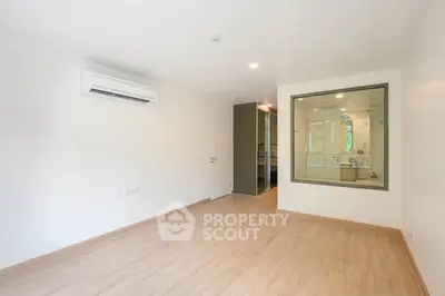 Spacious unfurnished room with large window and air conditioning, perfect for customization.