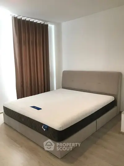 Spacious bedroom with modern bed and elegant curtains, perfect for relaxation.