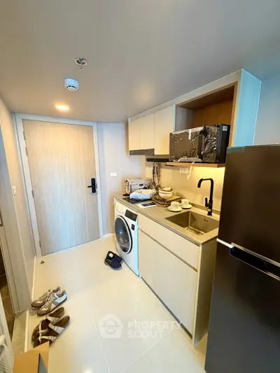 Modern compact kitchen with washing machine and sleek appliances in a stylish apartment.