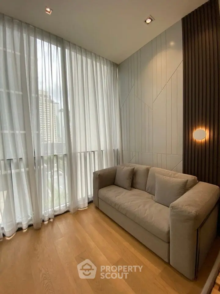 Modern living room with floor-to-ceiling windows and cozy sofa in a stylish apartment.