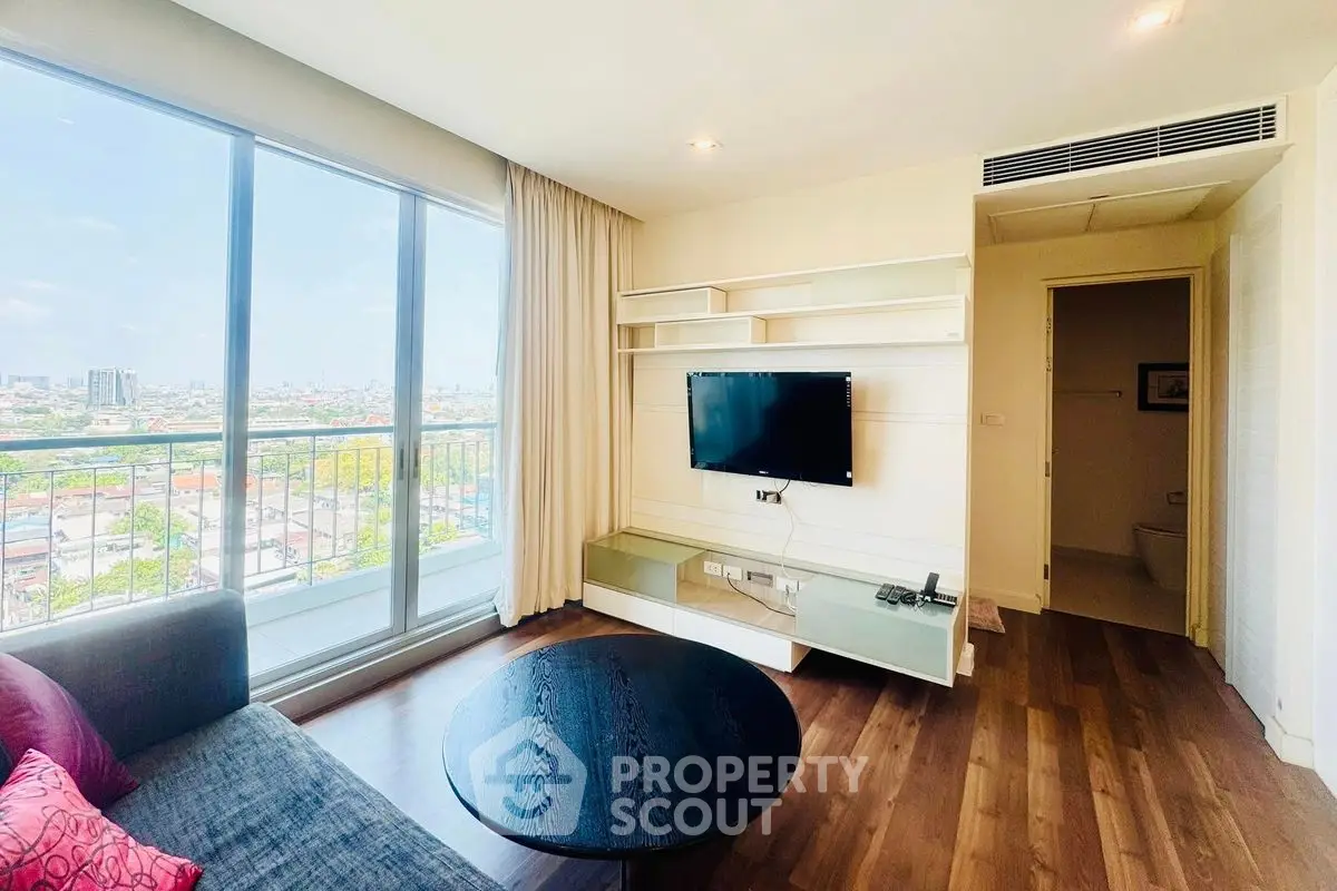 Modern living room with city view and balcony access, featuring sleek TV setup and cozy seating area.