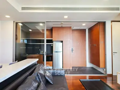 Modern living room with sleek kitchen and stainless steel fridge in open layout apartment.