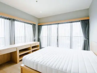 Spacious bedroom with large windows and natural light in modern apartment.