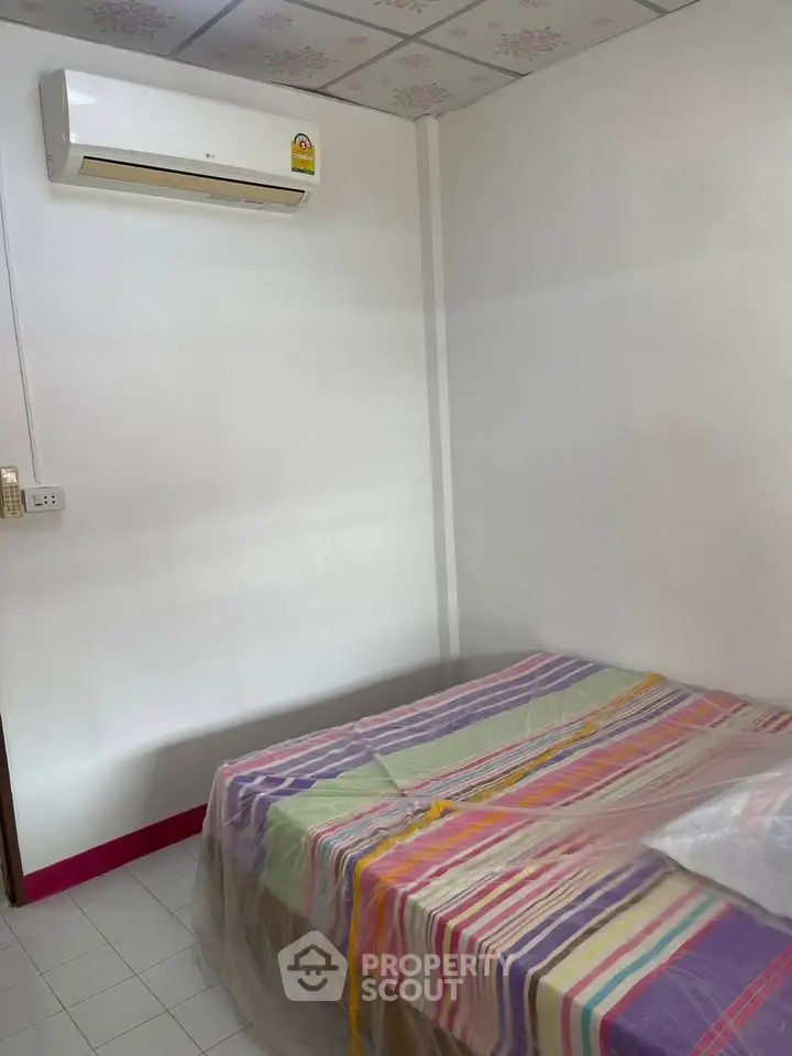 Cozy bedroom with air conditioning and colorful bedding, perfect for comfortable living.