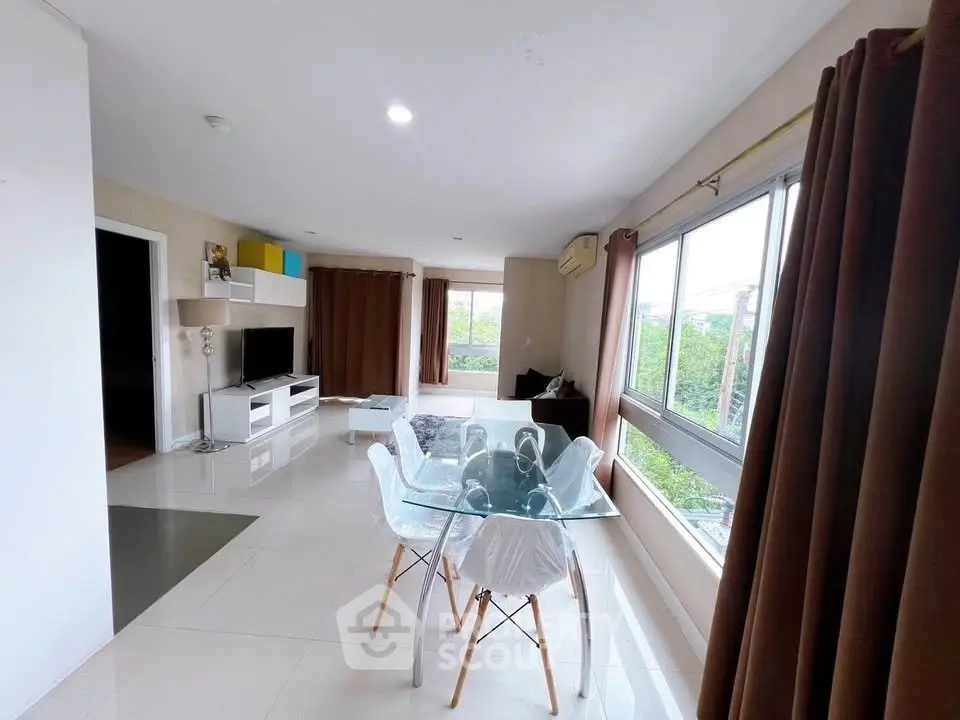 Spacious modern living room with large windows and stylish glass dining table.