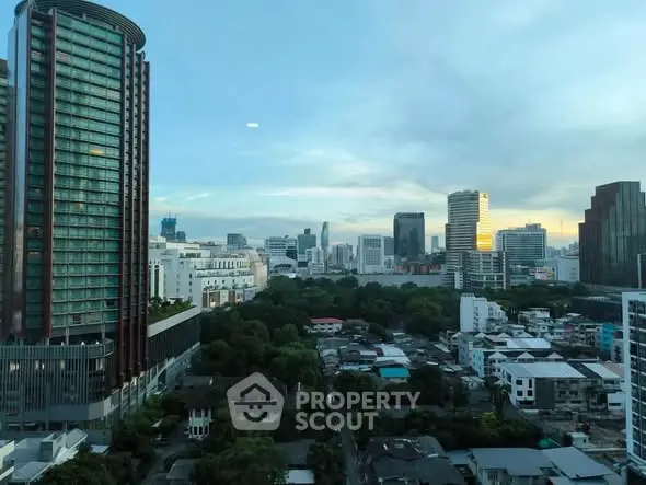 Stunning cityscape view from high-rise building showcasing urban skyline and lush greenery.