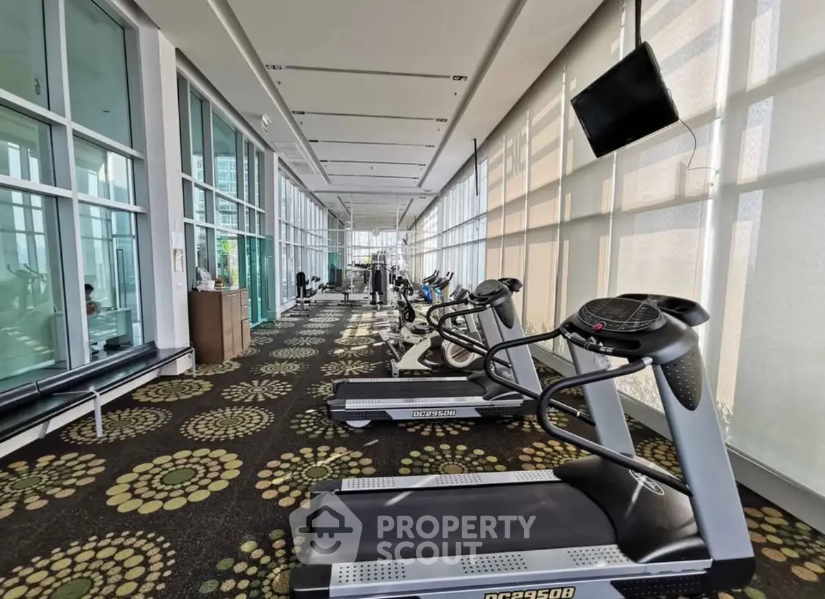 Spacious gym with modern treadmills and large windows offering natural light.