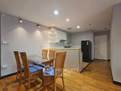 Modern kitchen with dining area featuring wooden flooring and sleek cabinetry.