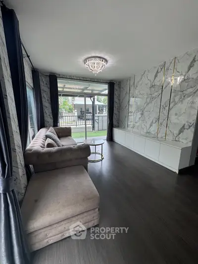 Luxurious living room with elegant marble wall and plush sofa, overlooking a serene outdoor view.