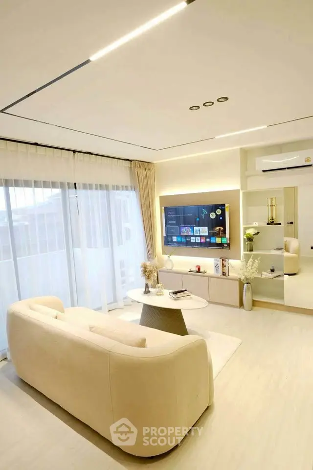 Modern living room with sleek design and large windows, featuring a wall-mounted TV and stylish furniture.
