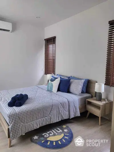 Modern bedroom with stylish decor and cozy ambiance, featuring a neatly made bed and wooden blinds.