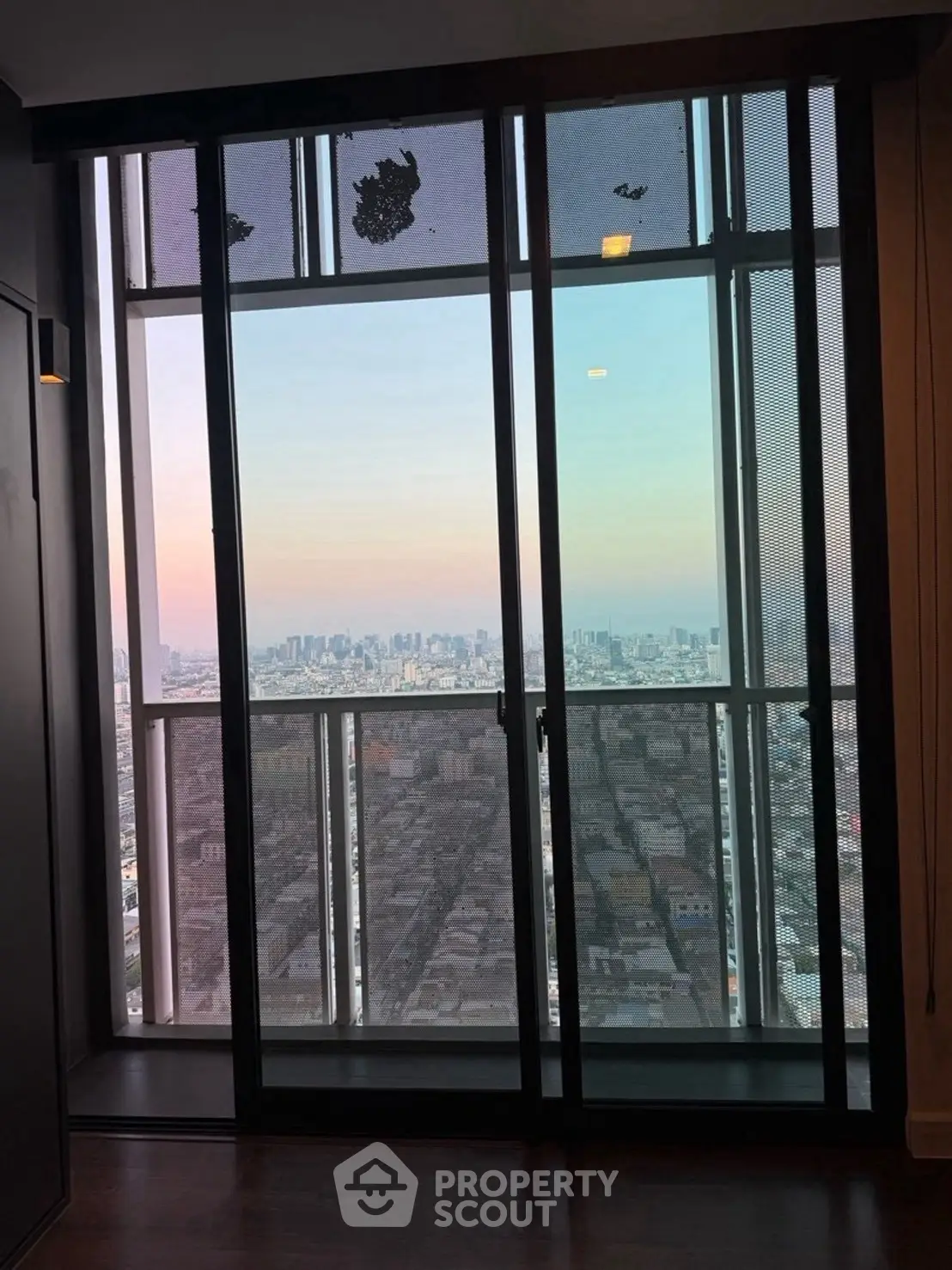Stunning high-rise city view from a modern apartment window at sunset.