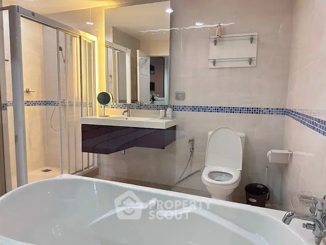 Modern bathroom with bathtub, shower, and sleek vanity in a stylish real estate property.