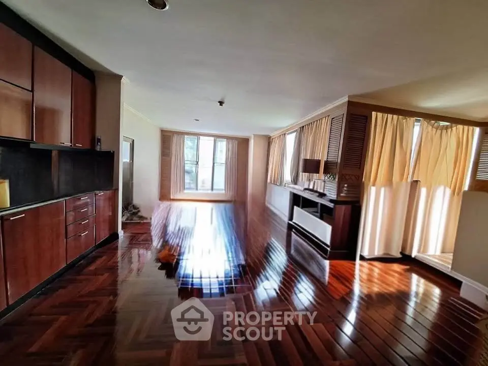 Spacious living room with glossy wooden floors and ample natural light.