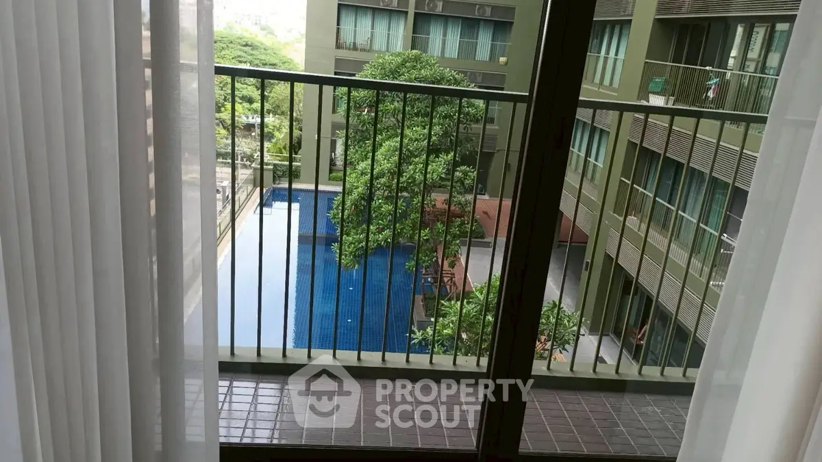 Modern apartment balcony with pool view and lush greenery