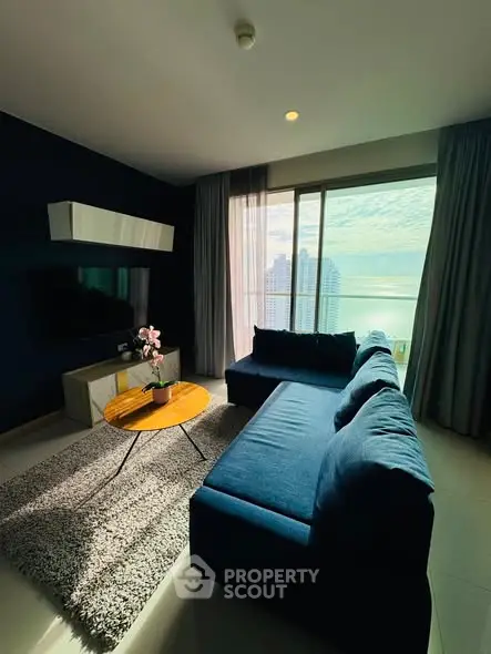 Modern living room with ocean view, featuring a stylish blue sofa and sleek decor.