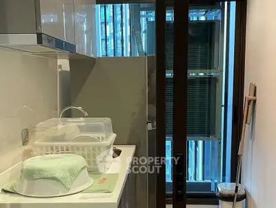 Compact kitchen with modern appliances and city view through glass door.
