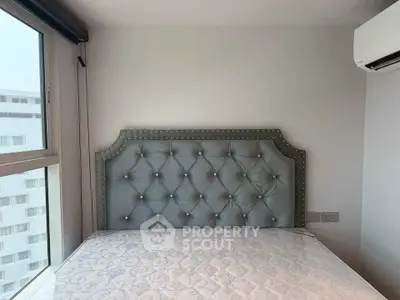 Modern bedroom with elegant tufted headboard and large window view.