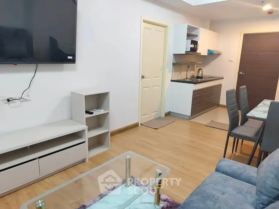 Modern open-plan living room with kitchen, featuring sleek furniture and wooden flooring.