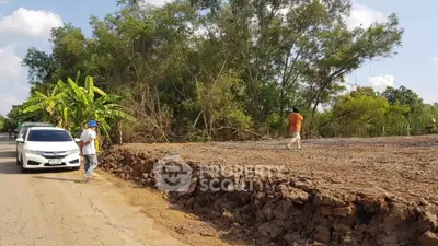 Vacant land plot with potential for development surrounded by lush greenery and accessible road.