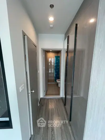 Modern hallway leading to a compact bathroom with sleek design.