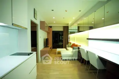 Modern living room with sleek design and open kitchen layout, featuring stylish furniture and ample lighting.
